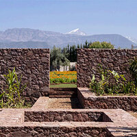 Garden with stone walls and mountains in the background.