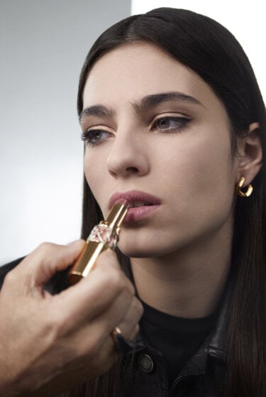 A hand applying makeup to a woman's face.