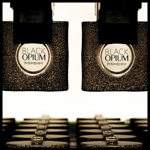 Two bottles of Yves Saint Laurent Black Opium perfume on a production line.