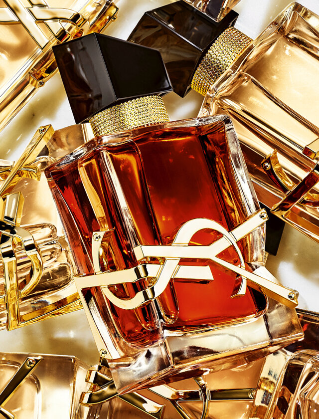 Several YSL perfume bottles with amber liquid and gold logos.