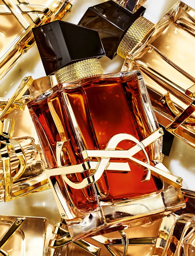 Several YSL perfume bottles with amber liquid and gold logos.