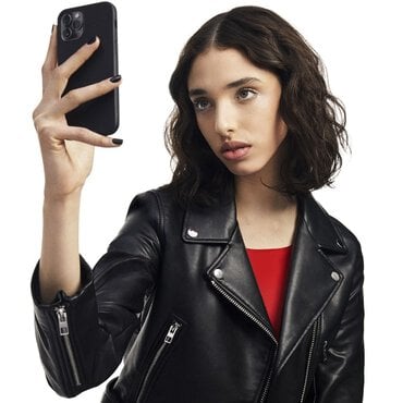 A woman in a black leather jacket holding a smartphone.