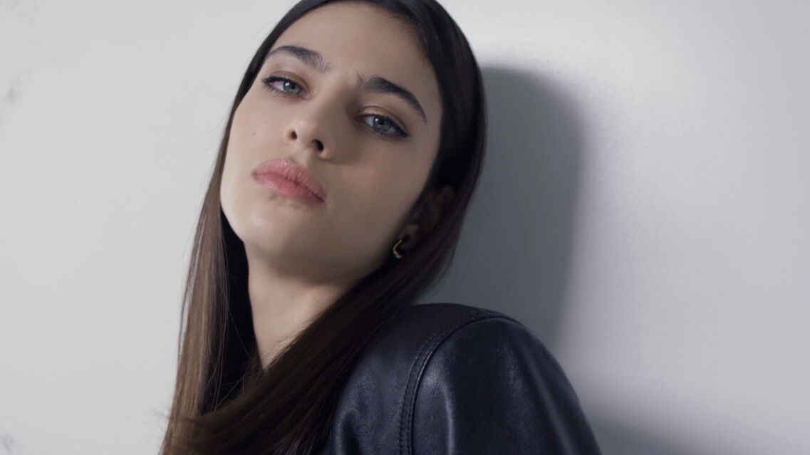 A woman with long hair wearing a black leather jacket.