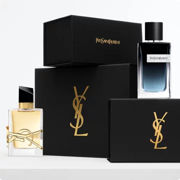 Two YSL perfume bottles, one with amber liquid and the other with blue liquid, placed next to black YSL branded boxes.