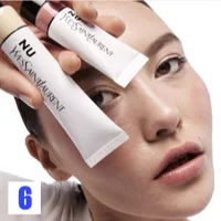 A person holds tubes of YSL Nu foundation near their face.