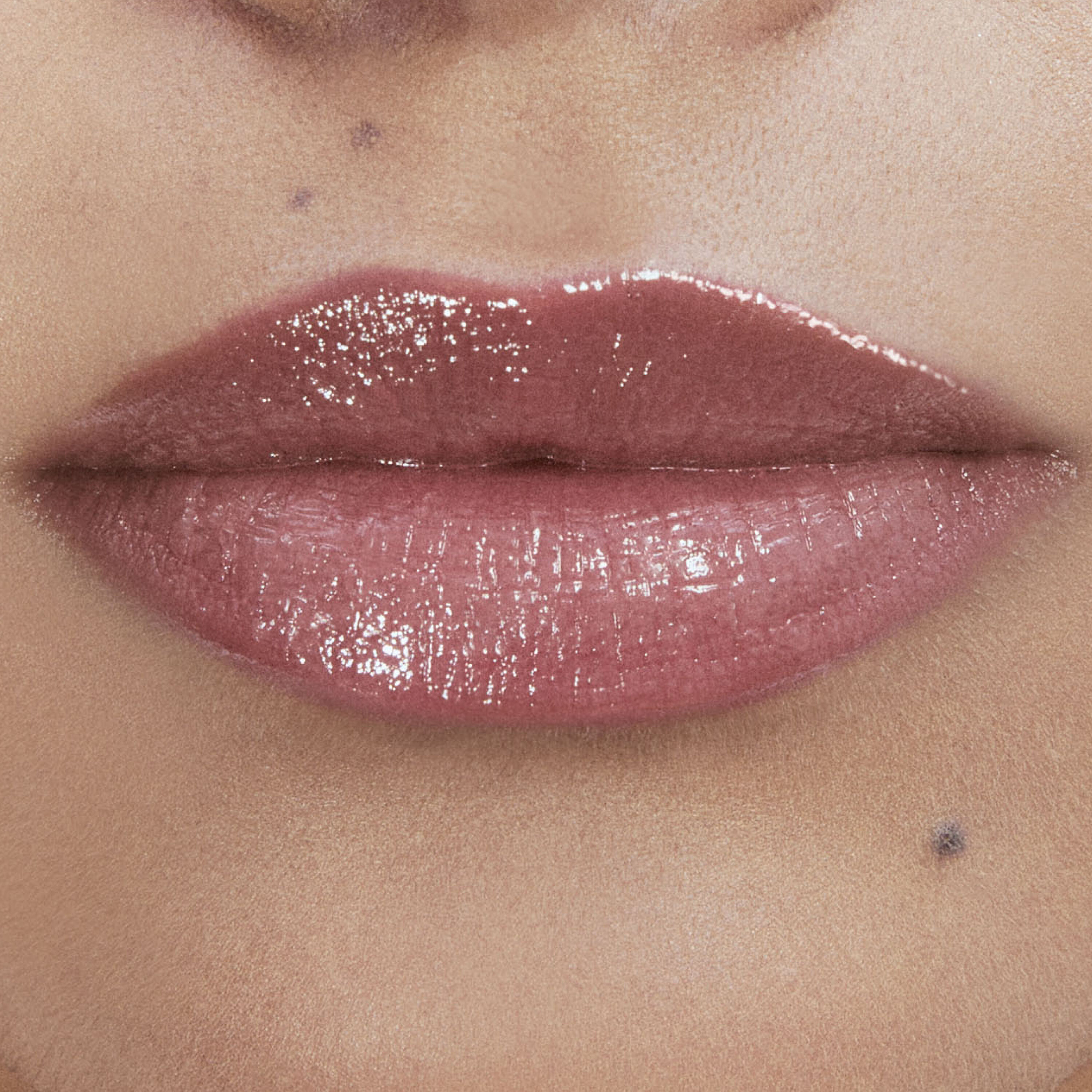 Close-up of lips with glossy pink lipstick.
