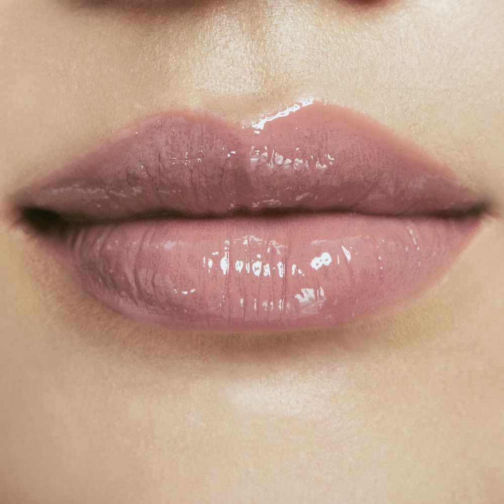 Close-up of lips with a glossy nude lipstick.