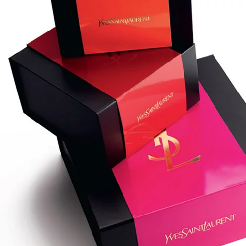 Stacked YSL gift boxes in red, black, and pink with gold logos.
