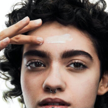 A person with curly hair and product swatched onto their forehead