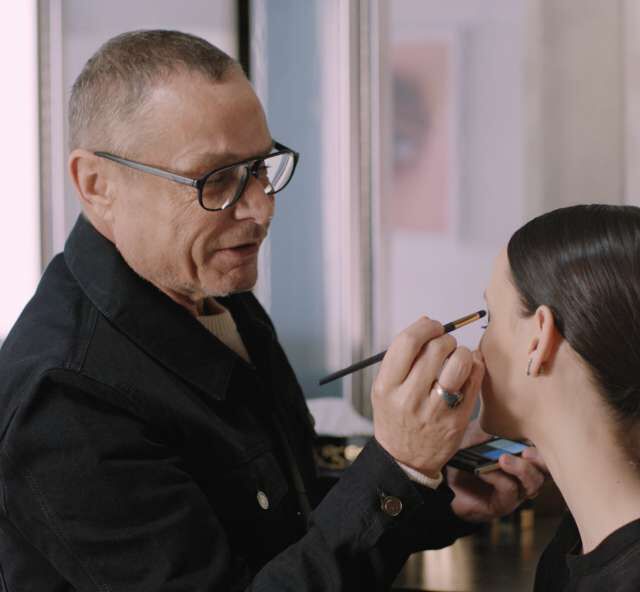 A makeup artist applies makeup to a woman's face.
