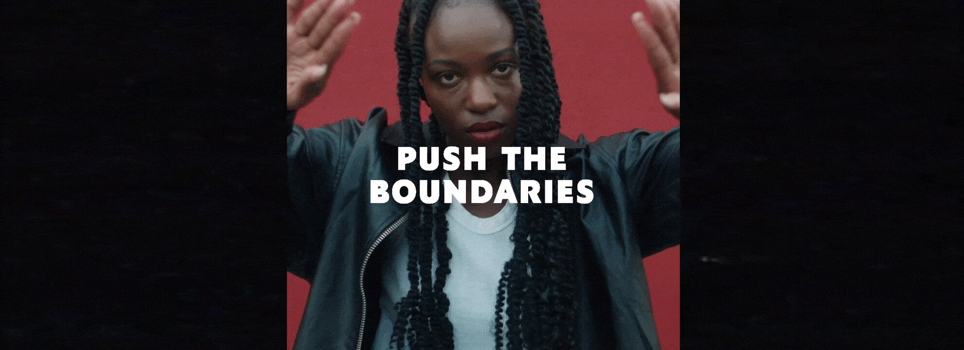 Push the boundaries text over a person with braided hair and a red background.