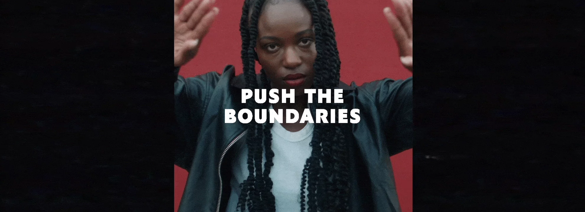 Push the boundaries text over a person with braided hair and a red background.