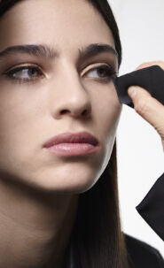 A person holding a piece of black fabric near their face.