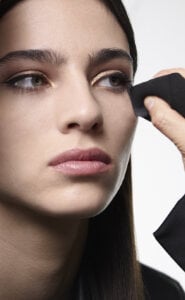 A person holding a piece of black fabric near their face.