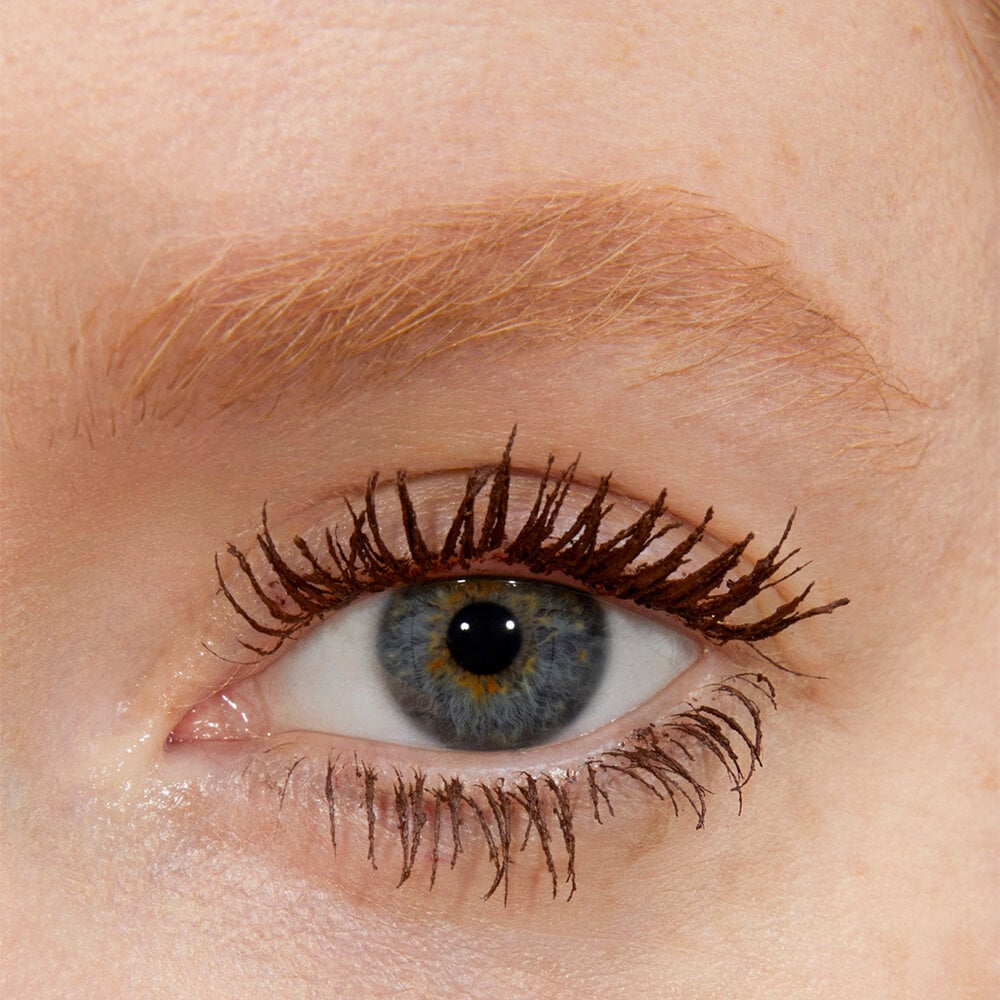 Close-up of an eye with long, curled eyelashes and light-colored eyebrows.