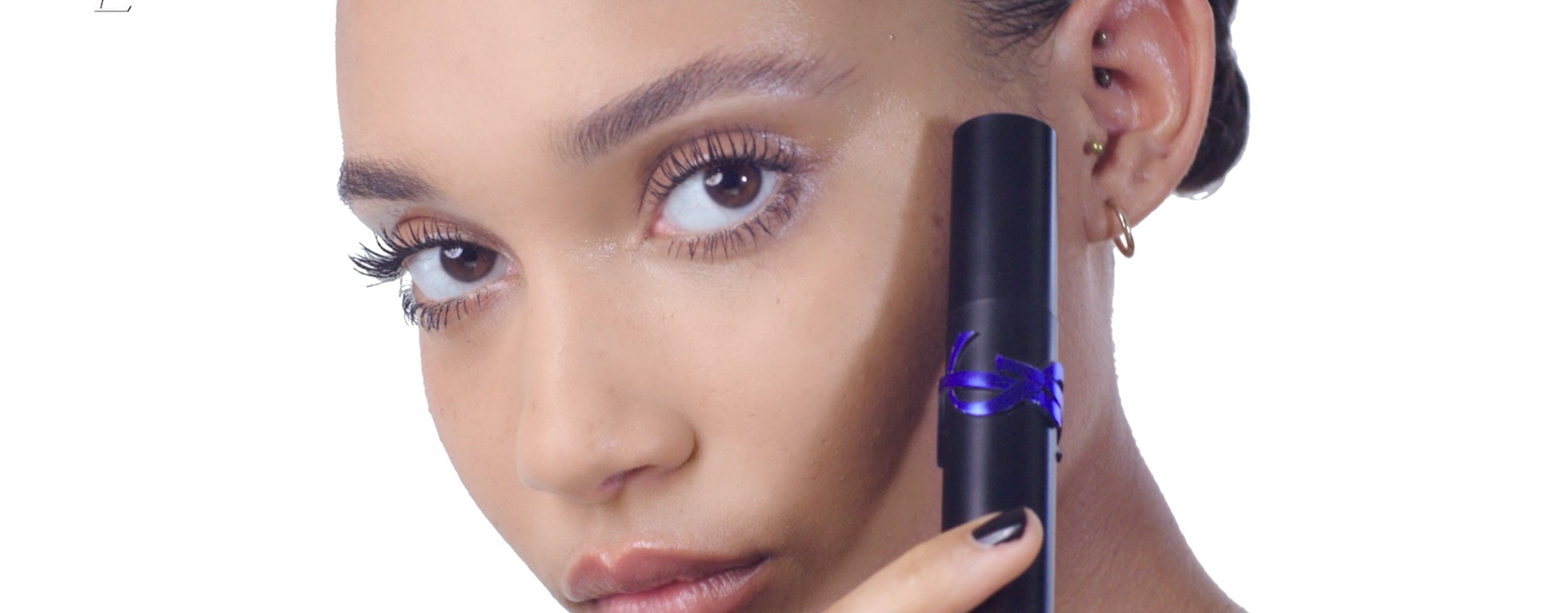 A person holds a YSL product near their face.