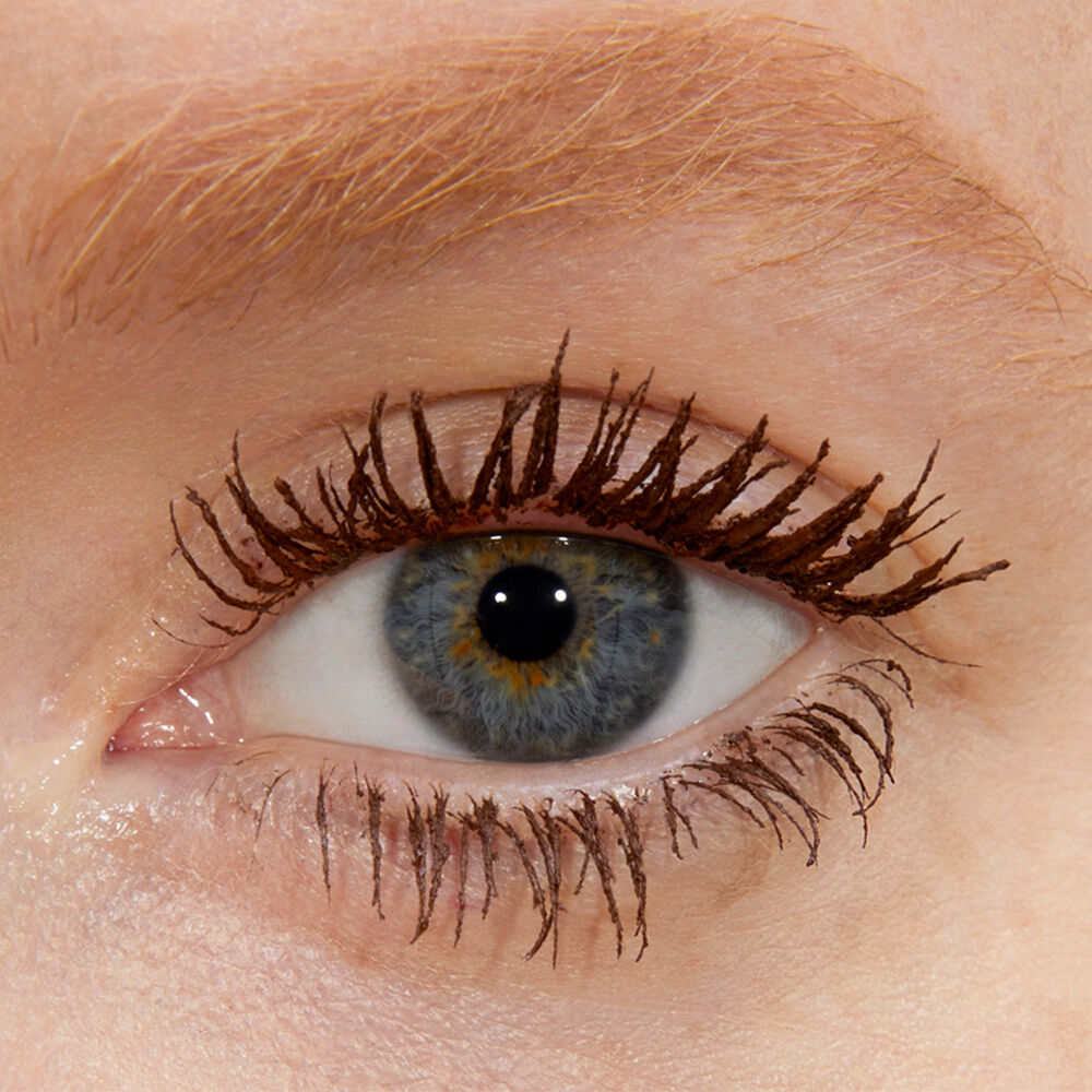 Close-up of an eye with brown mascara on the lashes.
