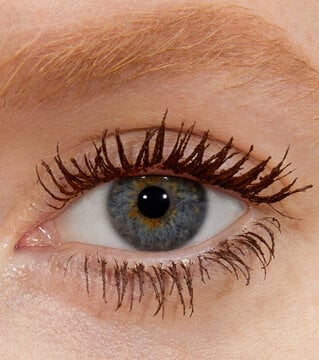 Close-up of an eye with brown mascara on the lashes.