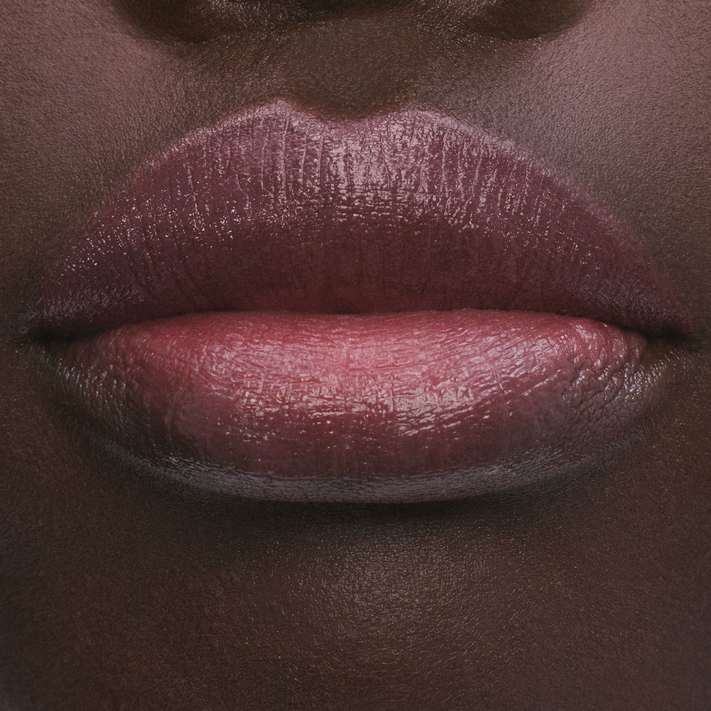 Close-up of lips with a glossy, deep pink lipstick.