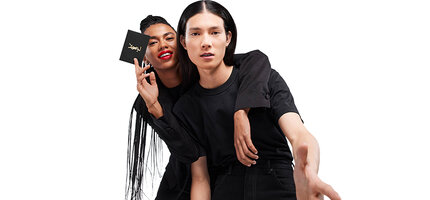 Two people holding a YSL e-gift card with the text 'E-Gift Card, Treat your loved ones to the perfect gift. Select the amount and add a message. The gift card isi delivered by email with instructions on how to redeem at checkout.'