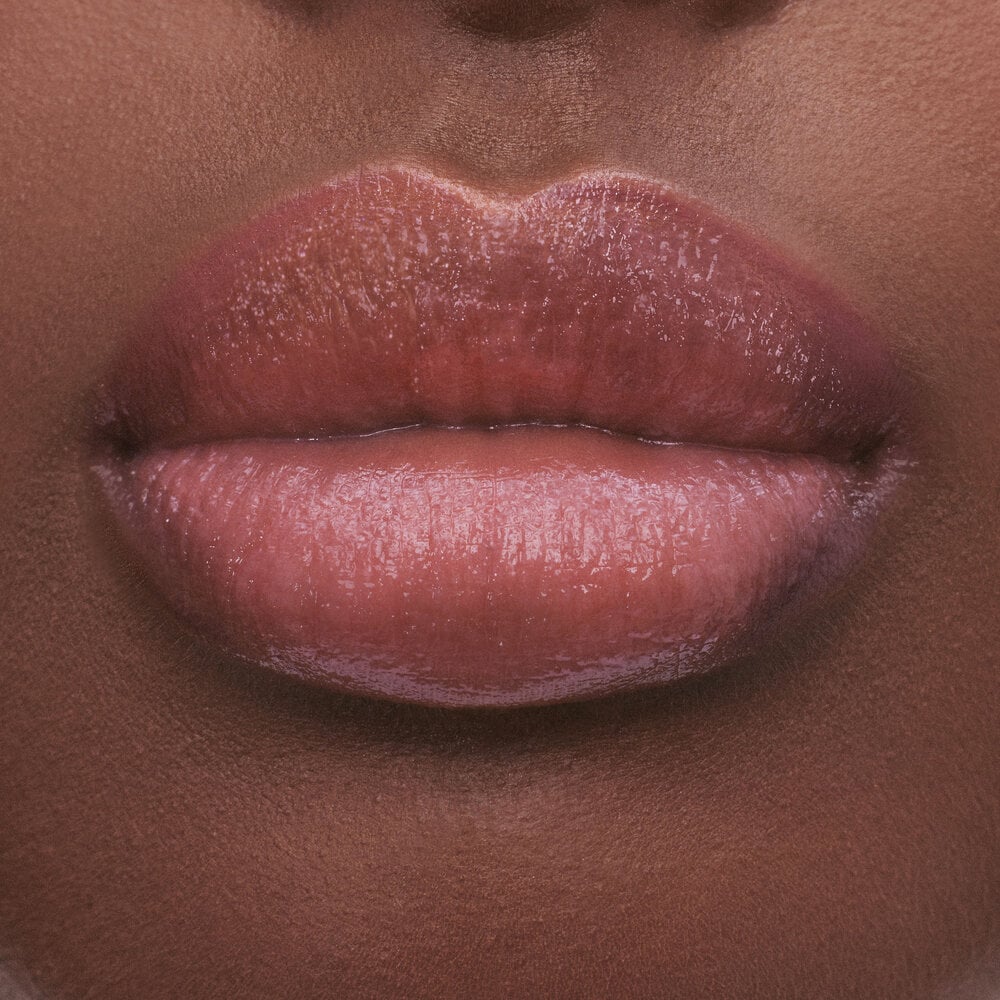 Close-up of lips with a glossy, natural pink lipstick.