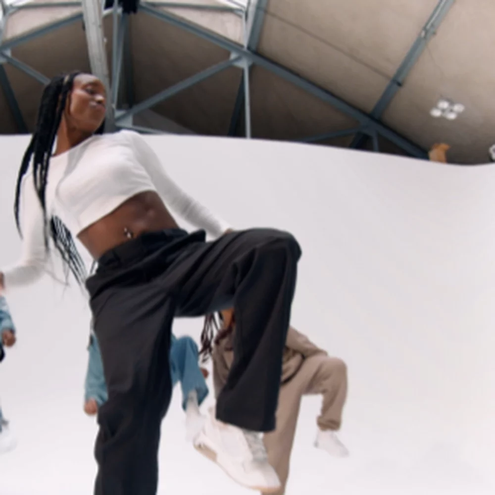 A dancer in a white top and black pants with text 'Cassie Dancer - Choreographer.'
