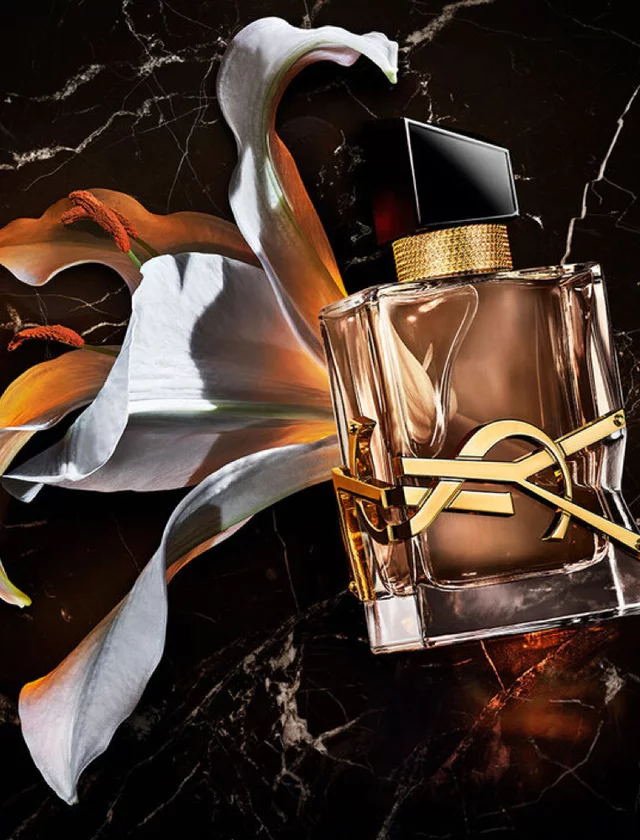 YSL perfume bottle with a white lily on a black marble background.
