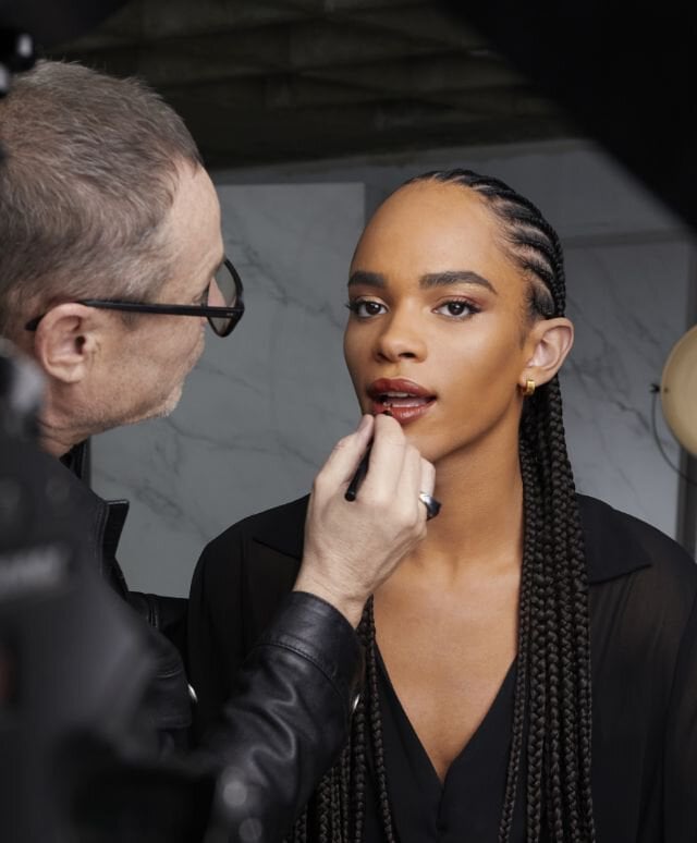 Makeup artist applying makeup to a person in a studio setting.