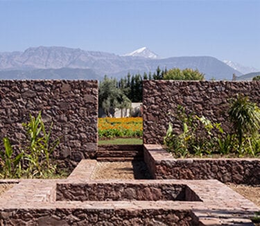 Garden with stone walls and mountains in the background.