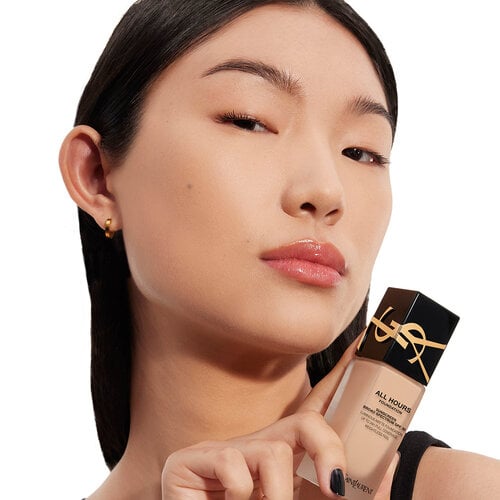 Close-up of model holding All Hours Foundation bottle