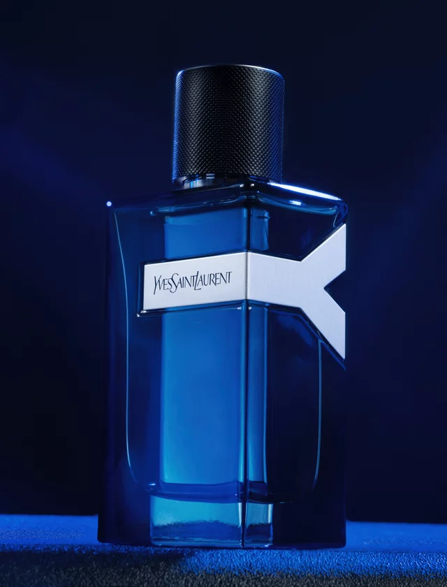 Yves Saint Laurent perfume bottle with dark blue liquid on a dark blue background.