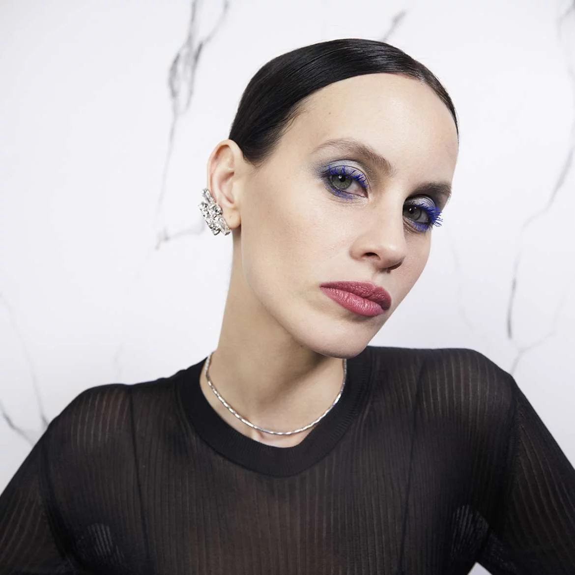 A person wearing a black top and silver jewelry.