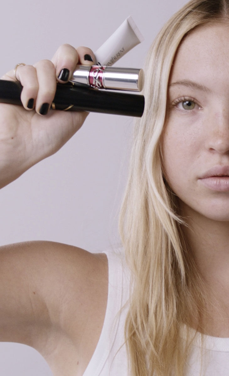 Person holding YSL beauty products.