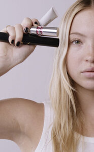 Person holding YSL beauty products.