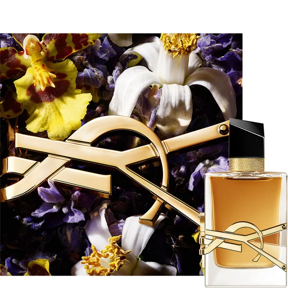 Rectangular YSL perfume bottle with amber liquid, surrounded by various flowers.