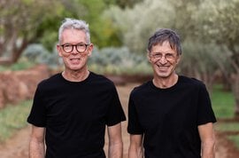 Two people in black shirts standing outdoors.
