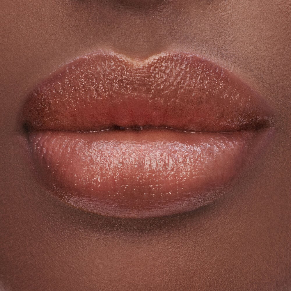 Close-up of lips with a glossy, warm brown lipstick.