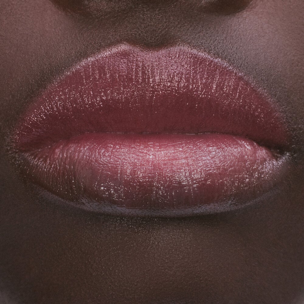 Close-up of lips with a glossy, dark pink lipstick.