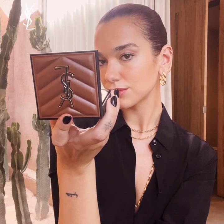 A person holding a YSL compact with a cactus in the background.