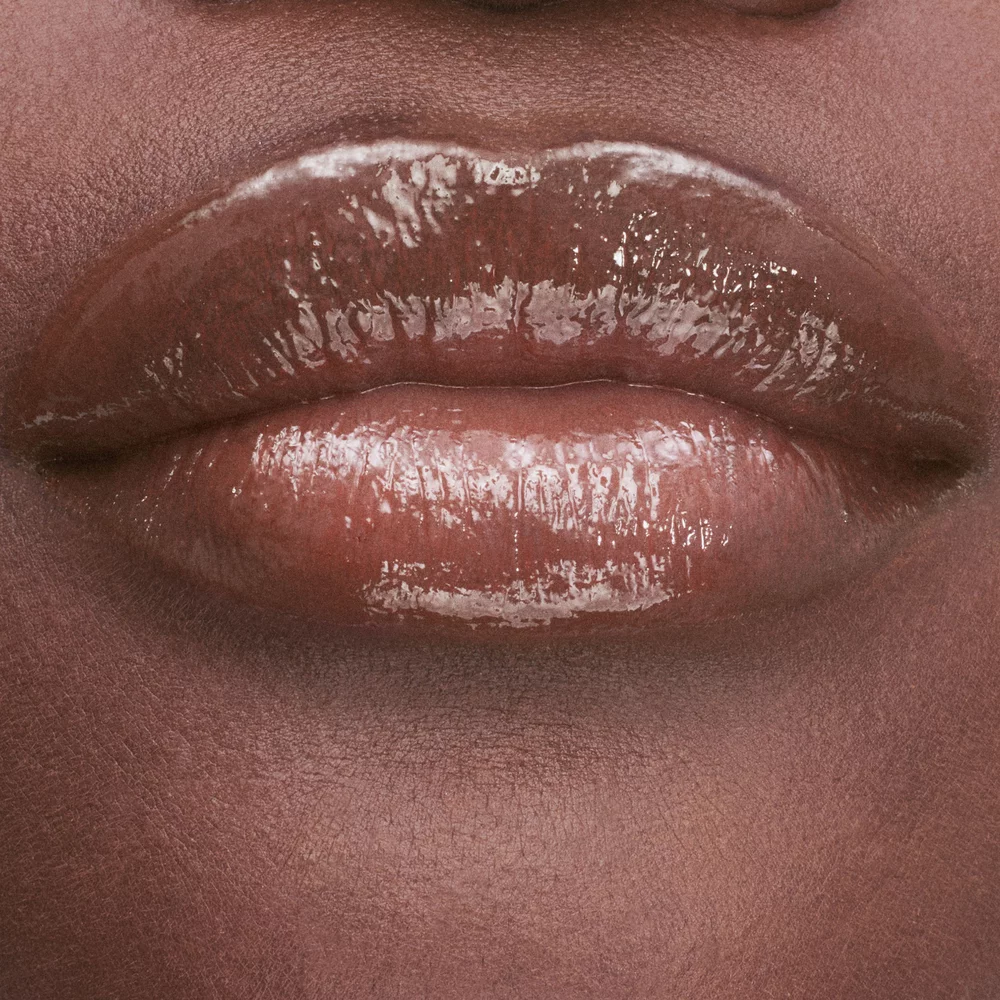 Close-up of lips with a glossy nude lipstick.