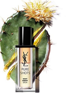 A bottle of YSL Pure Shots Night Reboot Serum with a cactus and flower in the background.