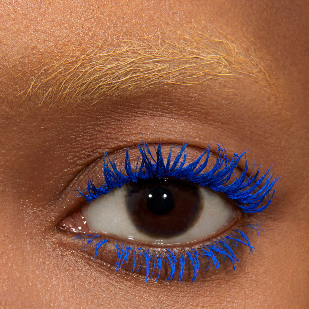 Close-up of an eye with bright blue mascara on the lashes.