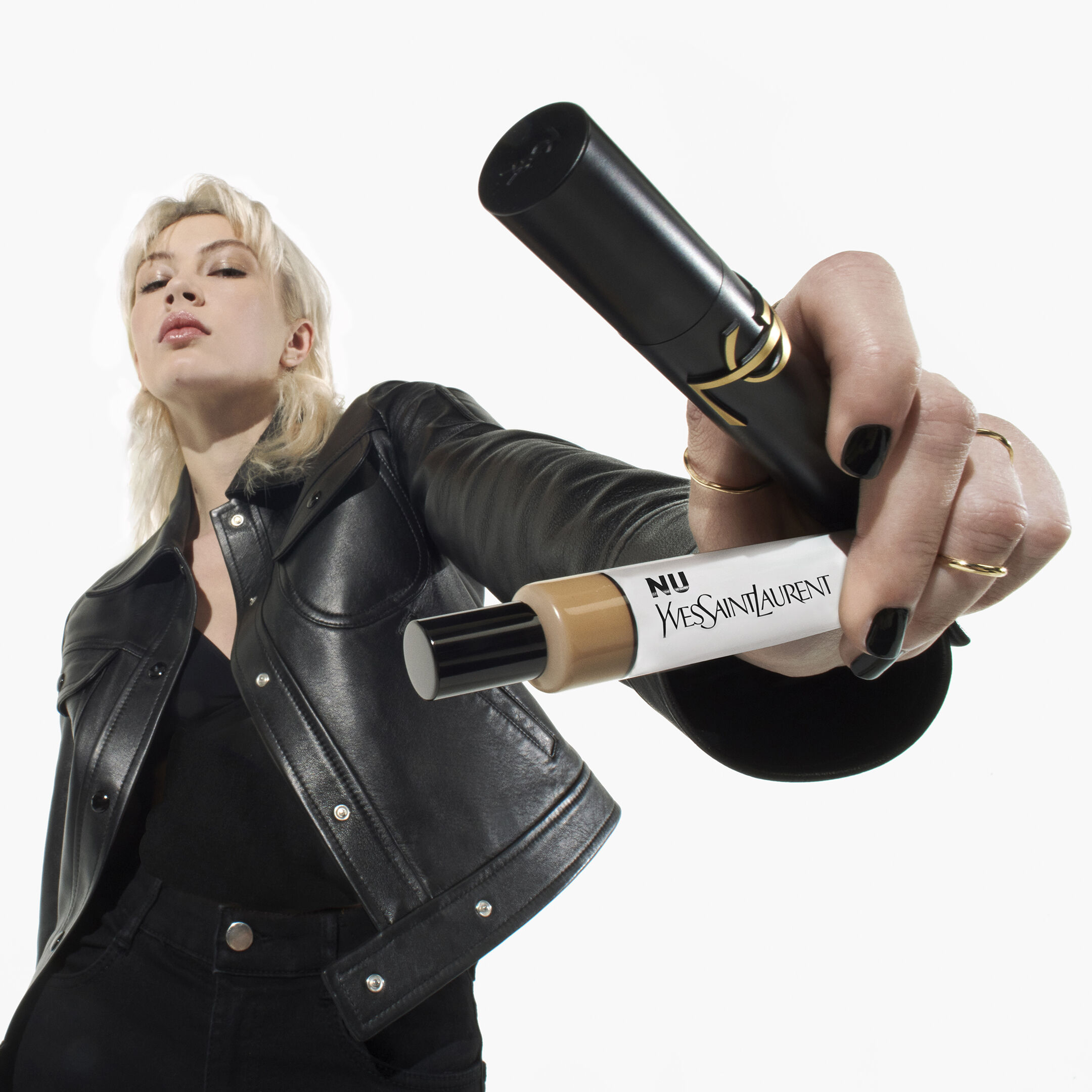 Person holding YSL Nu foundation and concealer tubes.