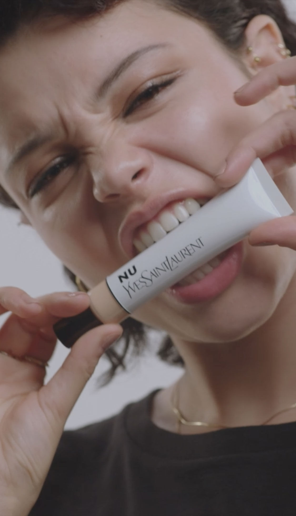 A person holding YSL Nu bottle between their teeth