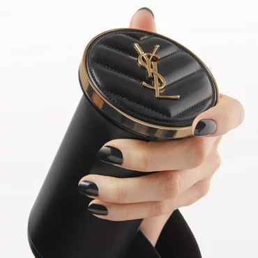 Hand holding a black cylindrical YSL product with a quilted leather top and gold YSL logo.