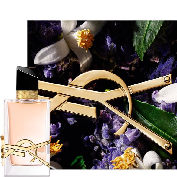 YSL perfume bottle with a gold logo in front of a background of flowers and leaves.