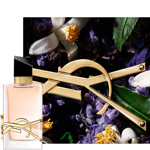 YSL perfume bottle with a gold logo in front of a background of flowers and leaves.