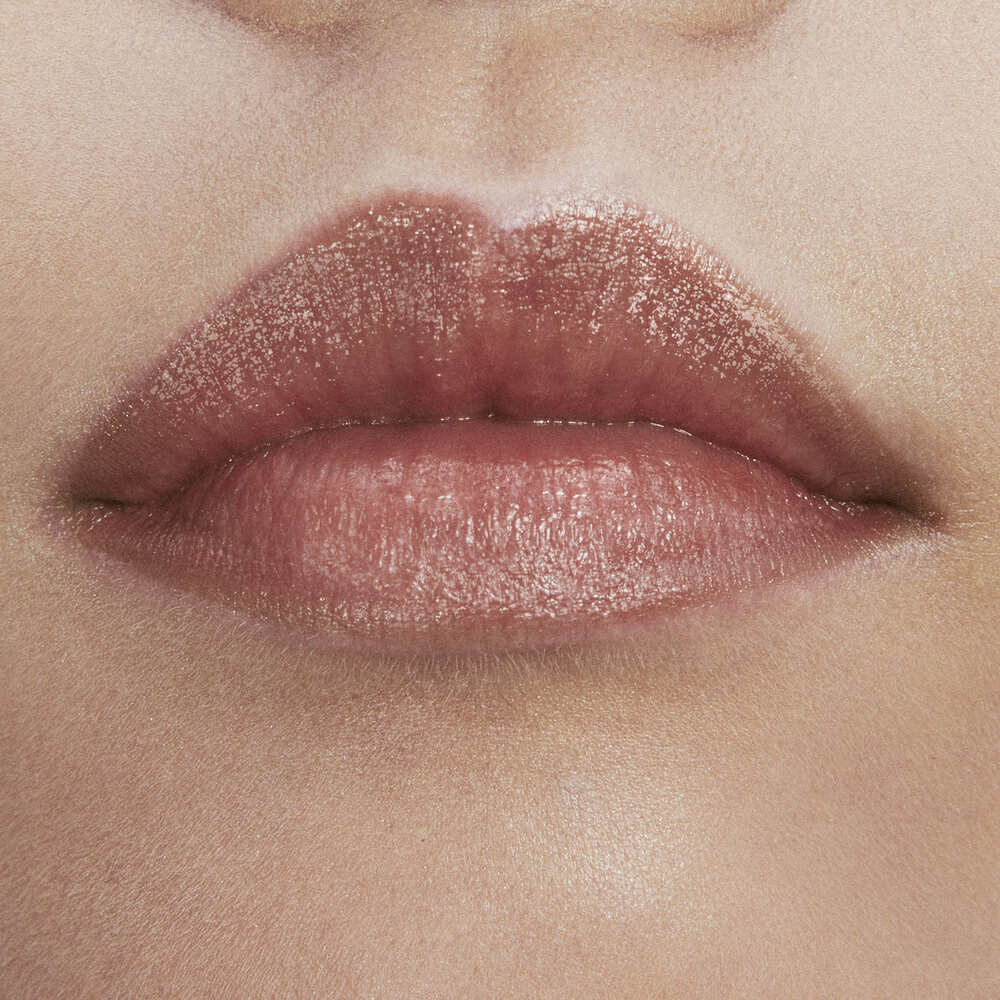 Close-up of lips with a glossy, light pink lipstick.