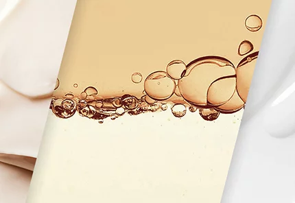 Formula droplets of serum in front of smears of whote moisturizer on a black square background.