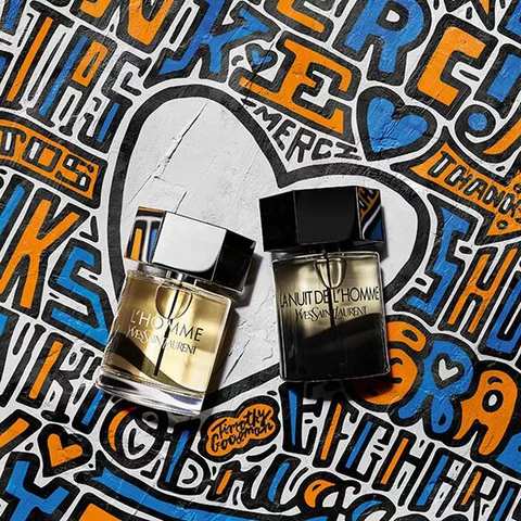 Two bottles of YSL L'Homme and La Nuit De L'Homme perfumes on a colorful graffiti background.